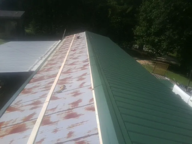 Old rusted panels beside newly installed green metal roofing — Wind Damage Roof Repair by Roofing Brothers in River Ranch
