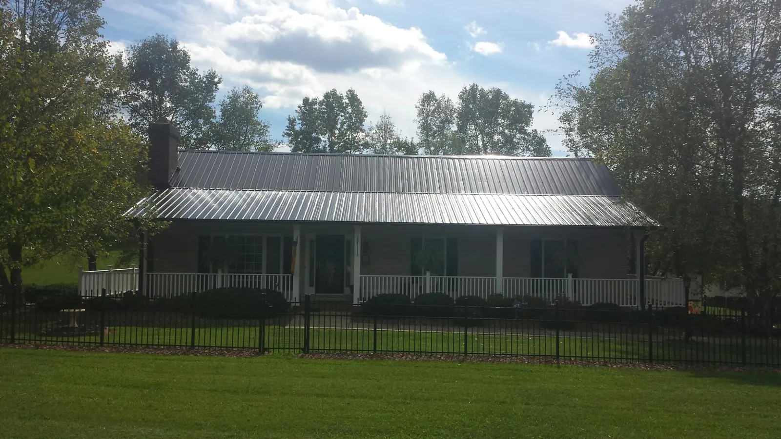Gray metal roof on a brick ranch with a full width front porch — Gutter Guard Installation work by our crew in River Ranch