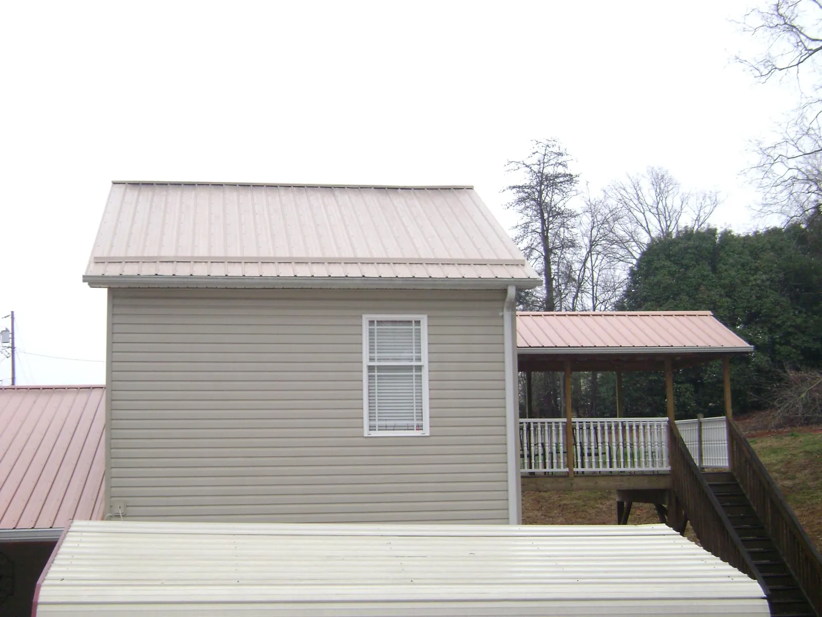 Tan metal roofs on a two story addition and attached porch, from a Roof Replacement job in River Ranch