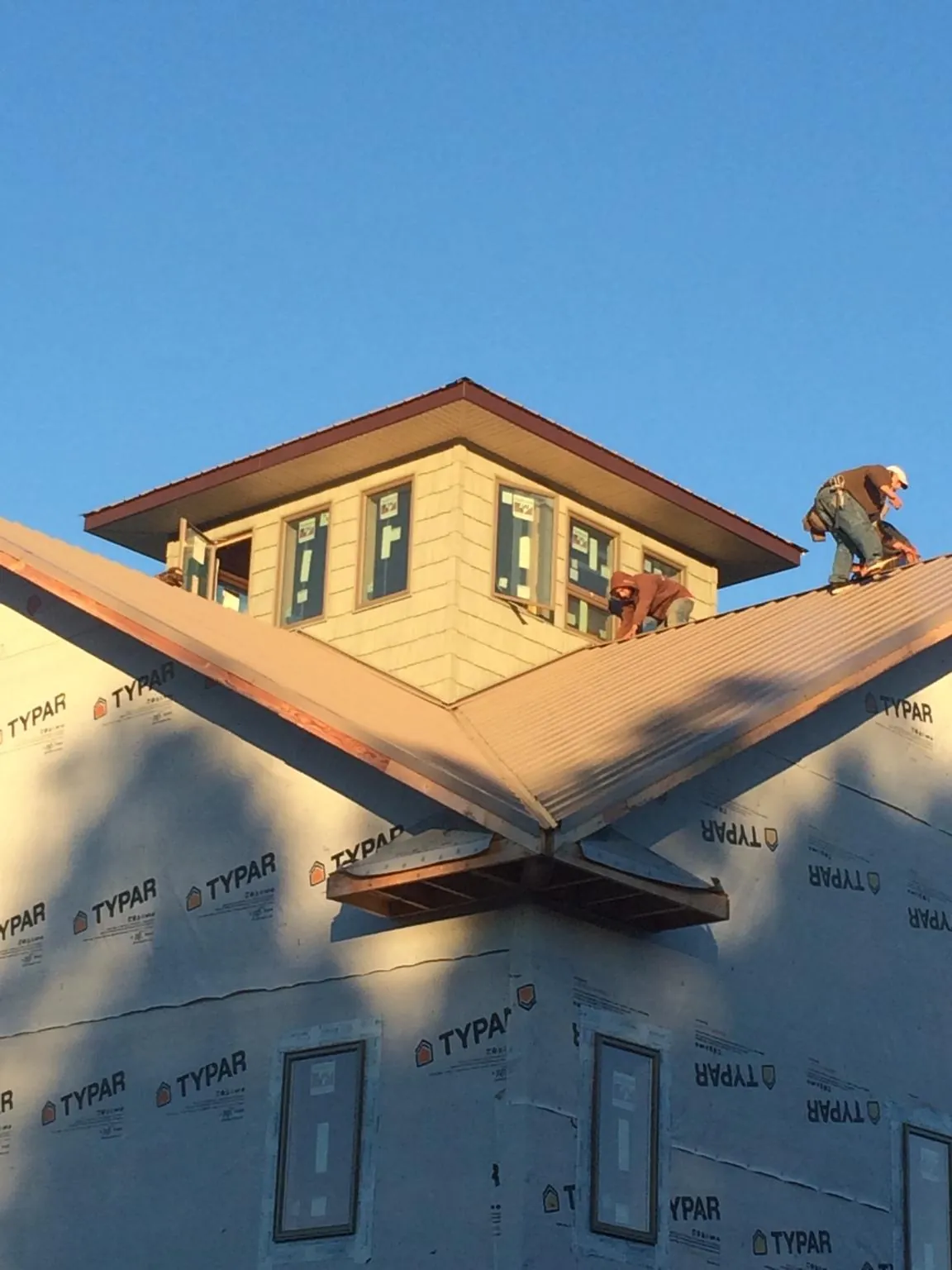 Roofers working around a rooftop cupola on a new metal roof at sunset — Roof Waterproofing in River Ranch by Roofing Brothers